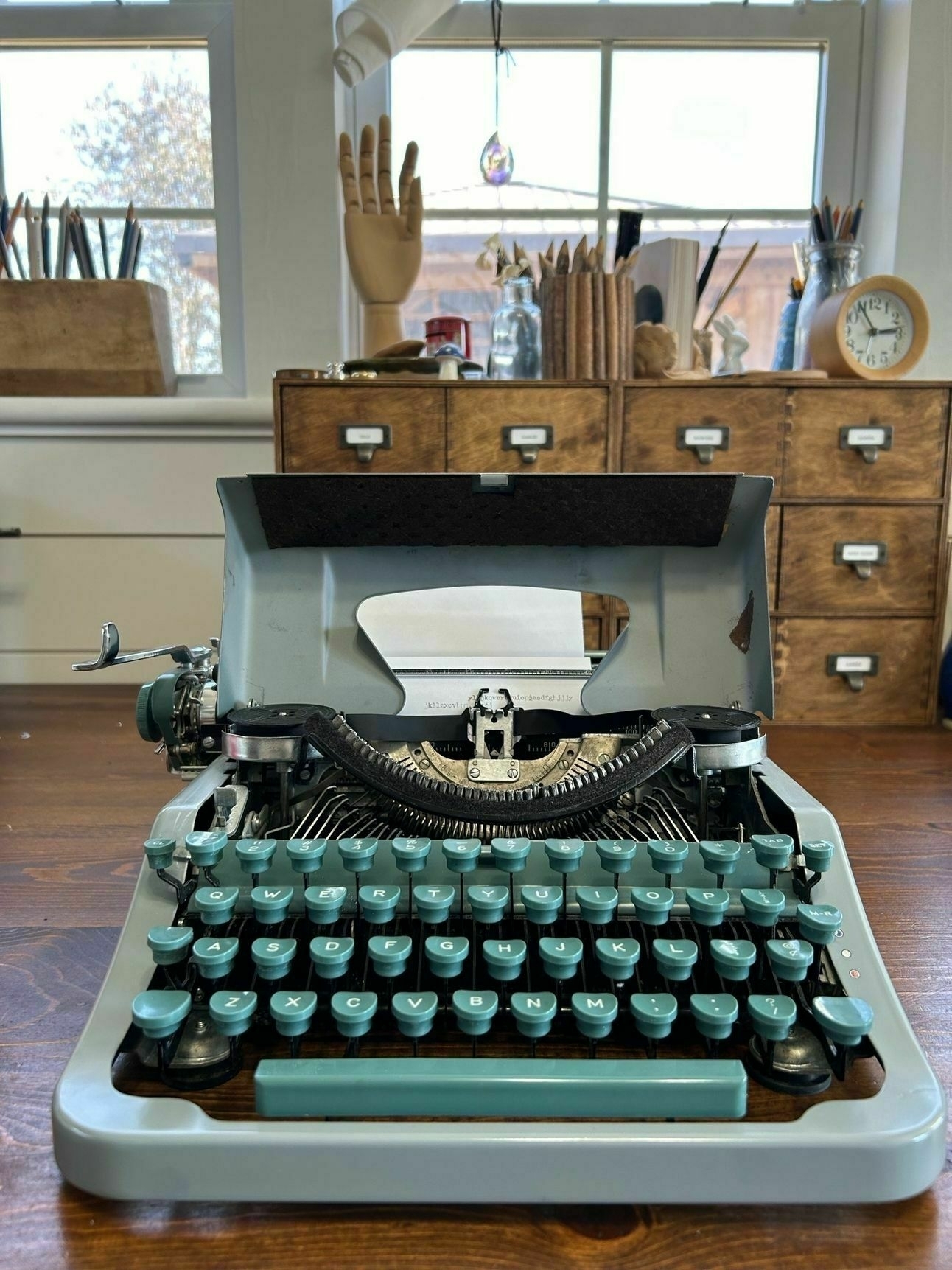 Green and gray Underwood typewriter sitws open on my desk. Library drawers int he back.