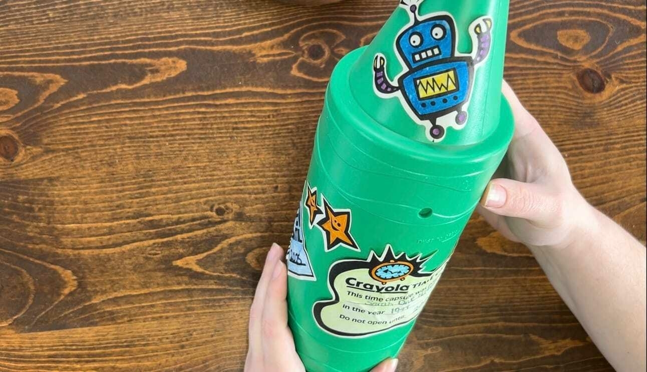 Green crayon shaped Crayola time capsule with robot and clock stickers.